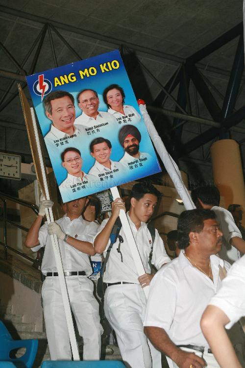 Supporters holding campaign poster of People's Action Party (PAP) candidates for Ang Mo Kio Group Representation Constituency (GRC) at Woodlands stadium, the assembly centre for PAP and their supporters during Singapore General Election