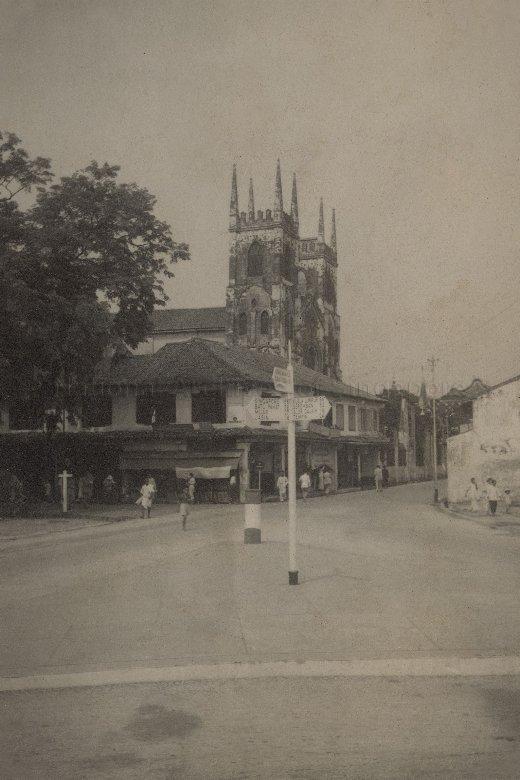 View of street in Malacca, with the double bell towers of St Francis Xavier Church in the background. Named after the Roman Catholic missionary who arrived in Malacca in 1545, the church was completed in 1856. Places on the directional sign pointing towards left include Singapore, Batu Pahat and Muar.