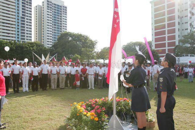 Flag-raising during observance ceremony at the National Day carnival and celebrations for Ang Mo Kio GRC and Yio Chu Kang, with Guest of Honour Prime Minister and Member of Parliament (MP) for Ang Mo Kio Group Representation Constituency (GRC) Lee Hsien Loong, MPs, grassroot leaders and guests standing at attention in the background