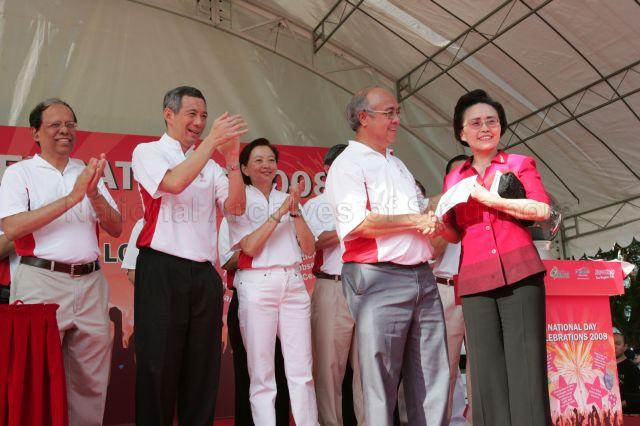 Guest of Honour Prime Minister Lee Hsien Loong, and other Members of Parliament for Ang Mo Kio Group Representation Constituency (GRC) Dr Balaji Sadasivan (left) and Ms Lee Bee Wah (third from left), applauding during presentation of cheque of $50,050, raised by grassroots groups and residents, for victims of the Sichuan earthquake. Receiving the cheque at the National Day carnival and celebrations for Ang Mo Kio GRC and Yio Chu Kang is China's Ambassador to Singapore Madam Zhang Xiaokang.