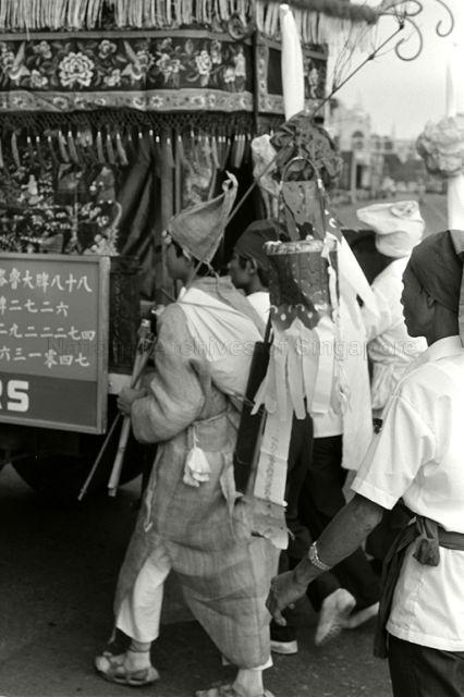 Eldest grandson carrying 'lantern' and mourners walking behind hearse at funeral procession Teochew opera boss of Lau Chet Kee Hiang at Clarke Quay