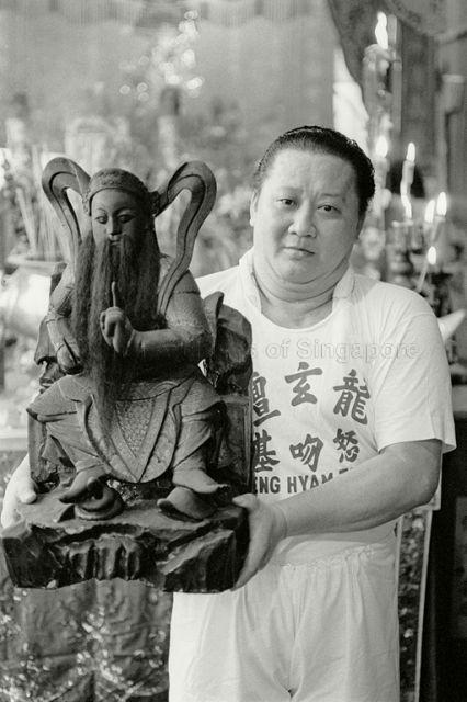 Devotee at Leng Hiang Tua temple with statue of Hiang Tian Siong Tay, a Taoist deity