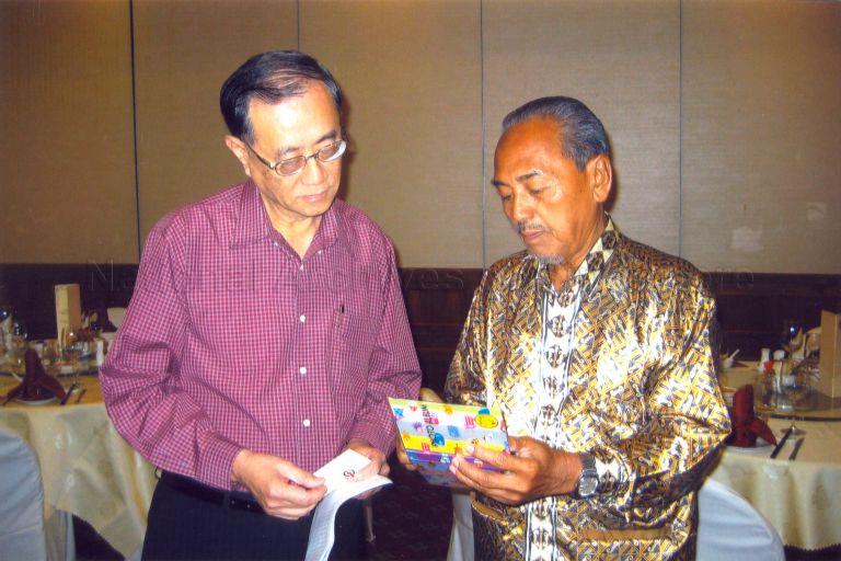 Photo depicts former People's Action Party (PAP) Member of Parliament, Mahmud Bin Awang showing photographs from his album to Lau Ping Sum, the former Member of Parliament for Yio Chu Kang.