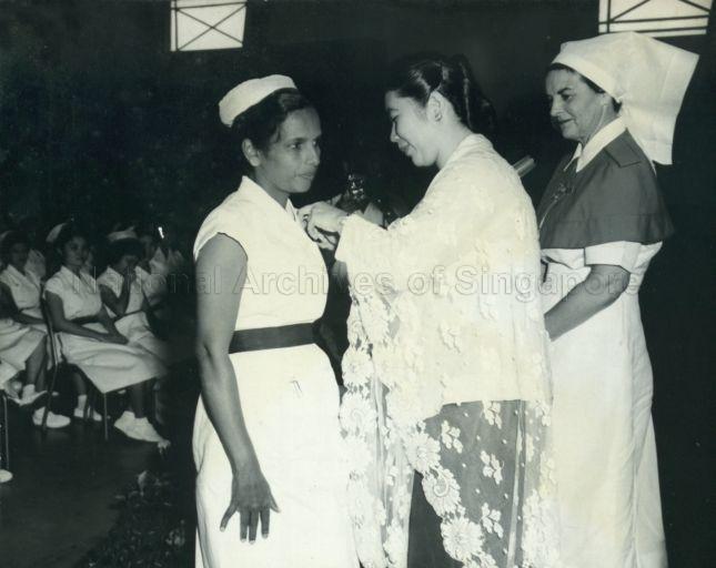 Puan Noor Aishah pinning a medal on a nurse at Nurses' Prize Presentation in the Allan Lecture Theatre at Sepoy Lines