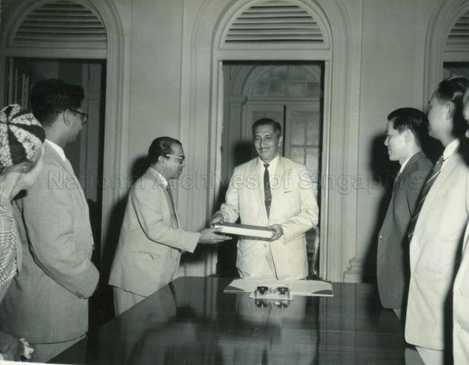 Yang Di-Pertuan Negara Yusof Ishak being presented with the Report of the Prison Inquiry Commission at the Istana Negara, by Chairman of the Commission C V Devan Nair