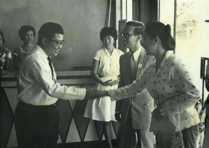 Puan Noor Aishah shaking hands with Lam Wai Seong, Assistant Commandant of Detachment, on arrival at the Chinese Young Men's Christian Association (YMCA) on her tour of the Red Cross Flag Day selling centres