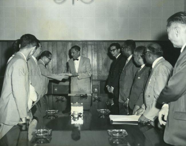 Yang Di-Pertuan Negara Yusof Ishak receiving the Education Enquiry Report from Professor Lim Tay Boh, Chairman of the Education Enquiry Commission, at Istana Negara