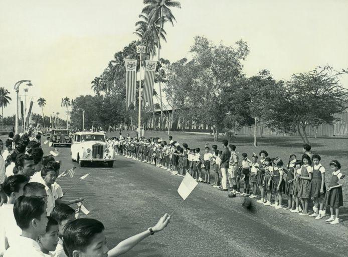 School children waving at the royal motorcade on its way to Paya Lebar Airport at the end of the state visit to Singapore by Yang Di-Pertuan Agong Tuanku Syed Putra and Raja Permaisuri Agong Tengku Budriah of Malaysia