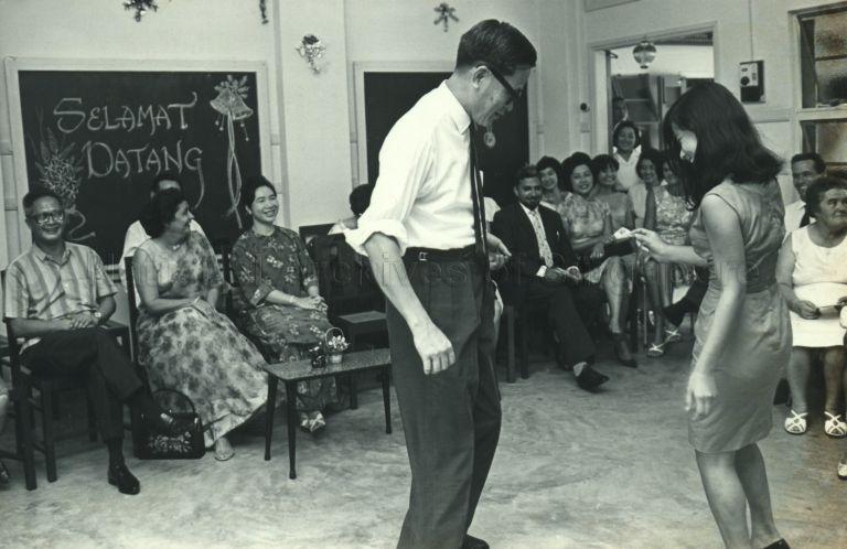 Puan Noor Aishah watching Minister for Health Yong Nyuk Lin on the dance floor at the children's Christmas party at Trafalgar Home