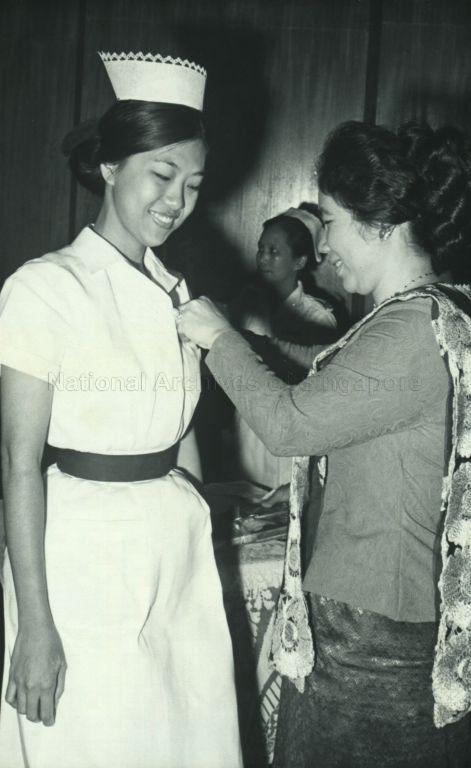 Puan Noor Aishah pinning the gold award for top nurse on Staff Nurse Jui Lan Eng at Nurses and Midwives Graduation Ceremony at Singapore Conference Hall