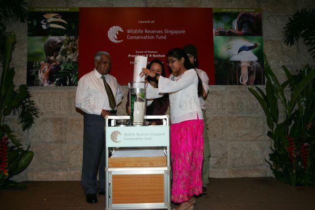 An Indian girl filling a time capsule with wishes for Singapore's wildlife made by the public, which is scheduled to be opened on 50th anniversary of Singapore Zoo in 2023, during launch of Wildlife Reserves Singapore Conservation Fund, an independent conservation fund dedicated primarily to native wildlife conservation and education, at the zoo in Mandai. On the left is President S R Nathan.