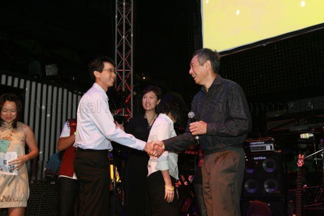 Prime Minister Lee Hsien Loong shaking hands with Mr Ang Kok Yong, one of his three assistants for a quiz on Chinese language and modern China, during launch of CLing, a new Chinese-learning media platform (cling.omy.sg) jointly presented by Business China and omy.sg (Singapore Press Holdings' bilingual news portal), at Dragonfly, St James Power Station in Sentosa Gateway. Also present on stage is Member of Parliament for Bishan-Toa Payoh Group Representation Constituency (GRC) and Chief Executive Officer of Business China Mrs Josephine Teo.