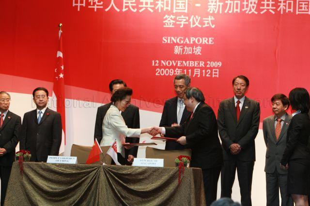 China's Ambassador to Singapore Madam Zhang Xiaokang and Head of Civil Service Peter Ho Hak Ean sealing the agreement with a handshake, witnessed by Chinese President Hu Jintao (face hidden) and Prime Minister Lee Hsien Loong at signing ceremony held at St Regis Hotel in Tanglin Road