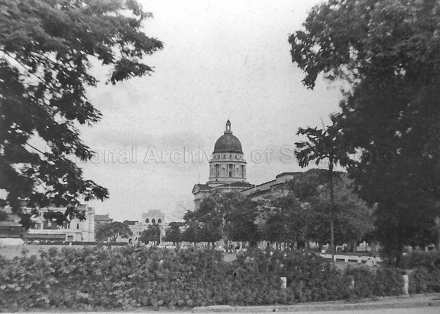View of Singapore Cricket Club (on left), Supreme Court (centre) and City Hall (behind trees) from across the padang, c.1950s
