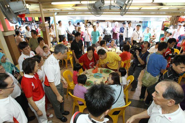Prime Minister Lee Hsien Loong touring a hawker centre during his walkabout in Teck Ghee Division of Ang Mo Kio Group Representation Constituency (GRC) after hongbao presentation ceremony held at Teck Ghee Community Club. Standing next to him is Member of Parliament for Ang Mo Kio GRC Lee Bee Wah (in red T-shirt).