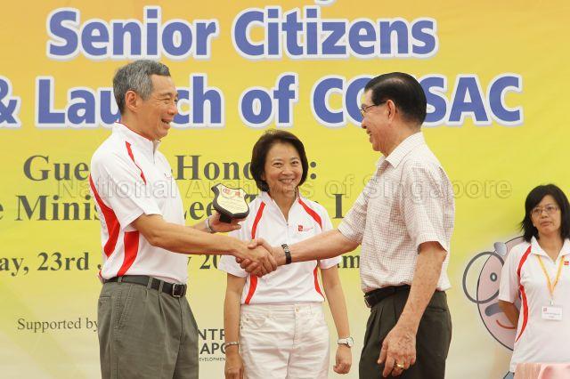 Prime Minister Lee Hsien Loong presenting token of appreciation during opening of Community Care Network (CCN) community fair for senior citizens and launch of CCN Senior Activity Centre (CCNSAC) at Block 420, Ang Mo Kio Avenue 10. Looking on is Member of Parliament for Ang Mo Kio Group Representation Constituency (GRC) Lee Bee Wah.