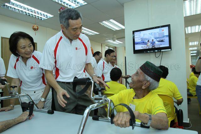 Prime Minister Lee Hsien Loong speaking to an elderly resident while touring Community Care Network Senior Activity Centre (CCNSAC) at Block 420, Ang Mo Kio Avenue 10, during opening of CCN community fair for senior citizens and launch of the activity centre. On the left is Member of Parliament for Ang Mo Kio Group Representation Constituency (GRC) Lee Bee Wah.