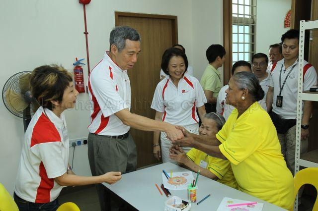 Prime Minister Lee Hsien Loong shaking hands with an elderly resident while touring Community Care Network Senior Activity Centre (CCNSAC) at Block 420, Ang Mo Kio Avenue 10, during opening of CCN community fair for senior citizens and launch of the activity centre. Looking on is Member of Parliament for Ang Mo Kio Group Representation Constituency (GRC) Lee Bee Wah (right).
