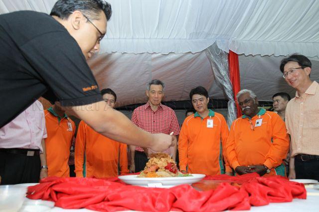 Prime Minister Lee Hsien Loong joining workers to toss yusheng during his visit to SembWaste Bukit Merah depot on the first day of Chinese New Year. Also present is Minister (Prime Minister's Office) and Secretary-General of National Trades Union Congress (NTUC) Lim Swee Say (right).