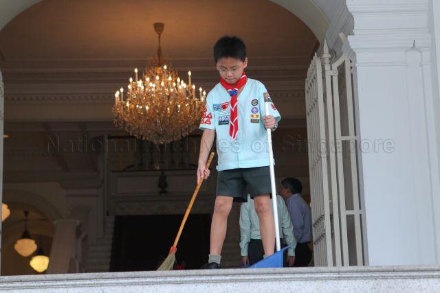 Scout sweeping the porch outside the front doors at Istana where President S R Nathan, Chief Scout of Singapore, launches scout job week to raise money for various scout activities