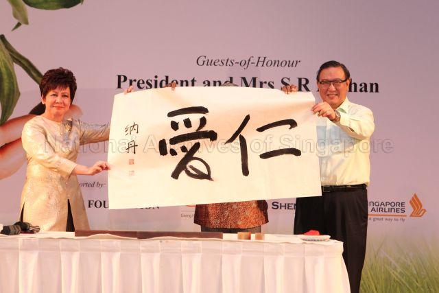 Chairman Gerard Ee and Chief Executive Officer Mrs Eunice Tay of National Kidney Foundation (NKF) displaying calligraphy piece with Chinese characters "ren ai" (仁爱 meaning benevolence) done by President S R Nathan for auction to raise funds during NKF's 100-table charity dinner at Grand Ballroom, Orchid Country Club