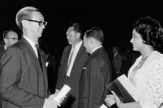 Visit to Singapore - Princess Norodom Monineath of Cambodia having a conversation with guests, with Prime Minister Lee Kuan Yew and Prince Norodom Sihanouk of Cambodia in the background