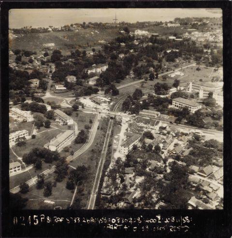 Aerial photo of the Alexandra Road, Ayer Rajah Road and Royal Road junction. The circus is Gillman Circus. Running right to left is Alexandra Road. Part of British Military Hospital (Alexandra Hospital) is next to it. On the near side of the road, bottom right of photo, is Alexandra Village. In the middle is the Malayan Railway line going under a bridge at Alexandra Road. The old Depot Road (before it was diverted to Lock Road) runs out into Alexandra beside the railway. The hill beside Depot Road was Railway Hill (then Gillman Heights and now The Interlace). In the background is Kent Ridge.