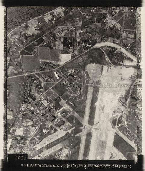 Aerial photo showing the southern half of RAF Tengah airfield, with Choa Chu Kang road bending around the end of runway 36. A new runway seems to be under construction with construction vehicles working on it.  Parked at the airfield are numerous English Electric Canberra bombers.  In September 1960, RAF transport aircraft had flown a dummy Red Beard atomic bomb to Tengah in preparation for deploying live nuclear weapons there.  48 live Red Beard atomic bombs were deployed to Tengah in August 1962.  They could have been delivered by Canberra bombers from low altitude, or V-bombers, like the Victor and Vulcan, from high altitude.