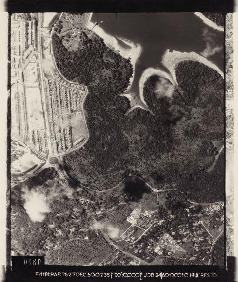 Aerial photo oriented with north down. Shows Peirce Reservoir, Sembawang Hills Estate (Seraya Crescent, Casuarina Road, Nemesu Avenue, Tembusu Road, Jacaranda Road, Sembawang Hills Drive, Jalan Telang, Jalan Kuras, Jalan Gelengang, Jalan Leban, Jalan Chempedak), Sembawang Hills Estate School, Sembawang Hills Circus, Yio Chu Kang Road, Old and New Upper Thomson Roads, Serangoon District Council Office, Hainan Village, Jalan Belang. Along the stretch of Old Upper Thomson Road behind Sembawang Hills Estate there used to be a weekly Pasar Malam. From 1961, the Singapore Grand Prix racing circuit ran along Old and New Upper Thomson Roads and Sembawang Hills Circus.