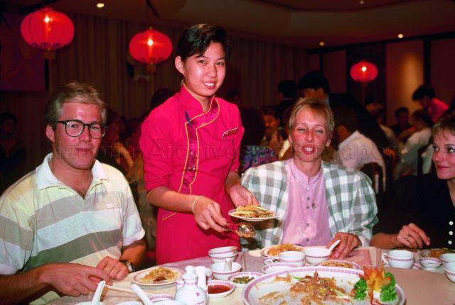Chinese restaurant waitress serving a table of tourists