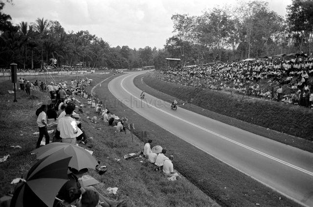 Victor Lee on a Honda CR 93 (number 6) leading Mohd Ali Rais on a Norton (number 8) leaving Range hairpin during third Malaysia Grand Prix (also known as Malaysian Grand Prix) held at Upper Thomson Road, Singapore