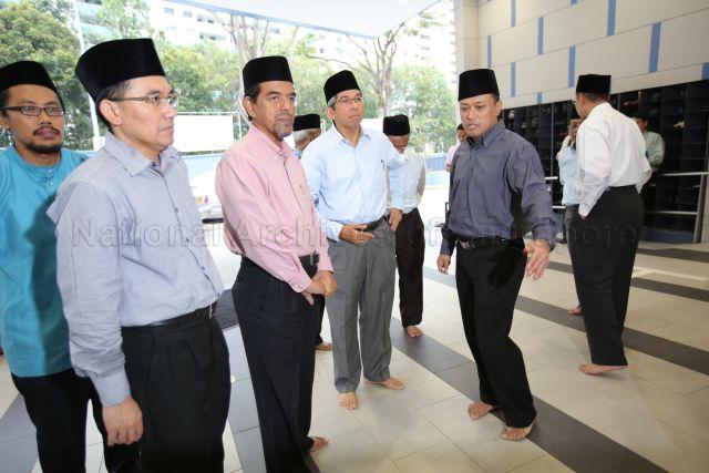 A group of men waiting at the lobby of An-Nur Mosque located at 6 Admiralty Road. Among those present are An-Nur Mosque Chairman Abdul Rahim Mawasi (in dark gray shirt) and Minister for Communications and Information and Minister-in-charge of Muslim Affairs Yaacob Ibrahim (center).
