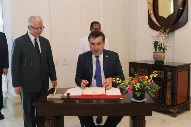 President of Georgia, Mikheil Saakashvili (wearing blue tie) signing guest book at Istana. Looking on is President Tony Tan Keng Yam (left).