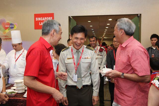 Prime Minister Lee Hsien Loong is speaking to an army general at National Day Parade 2013 at the Float @ Marina Bay. Defence Minister Ng Eng Hen is pictured on the right.