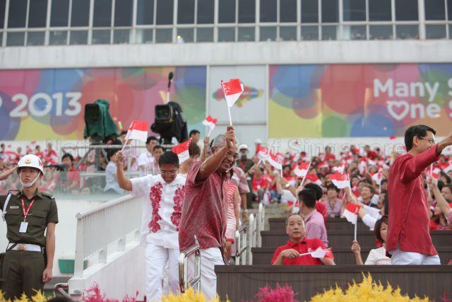 Senior Parliamentary Secretary for Education Hawazi Daipi (centre, standing) and Aljunied Group Representation Constituency Member of Parliament Low Thia Khiang (seated first row, to the right of Mr Hawazi) are attending National Day Parade 2013 at the Float @ Marina Bay.