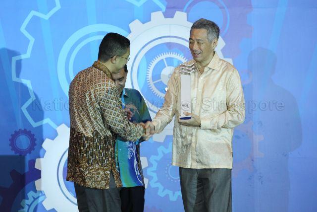 Prime Minister Lee Hsien Loong is presenting Berita Harian's Achiever of the Year Award to Dr Abdul Razakjr Omar at Shangri-La Hotel. Dr Abdul Razakjr is a cardiologist and he is honored for his achievements in his medical career.