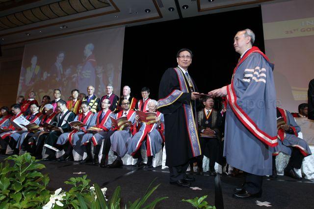 Master Academy of Medicine of Singapore Dr Lim Shih Hui (right) is presenting a certificate to President of the College of Surgeons in the Academy of Medicine of Malaysia Peter Wong Toh Lee (left) at Induction Comitia 2013 and 21st Gordon Arthur Ransome Oration at Grand Copthorne Waterfront Hotel. Also present are President Tony Tan Keng Yam and Minister of Finance Tharman Shanmugaratnam.