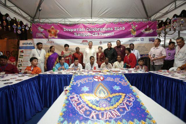 Prime Minister Lee Hsien Loong and (on his left) his wife Madam Ho Ching, (3rd from left) Senior Minister of State for Law and President of Singapore Indian Development Association (SINDA) Indranee Rajah and (7th from left) Minister (Prime Minister's Office), Second Minister for Home Affairs and Second Minister for Trade and Industry S Iswaran posing for a photo with officials and participants of Rangoli CD Project, during Deepavali Light-up ceremony at Kinta Road. Foreground is a birthday card for former Prime Minister Lee Kuan Yew.