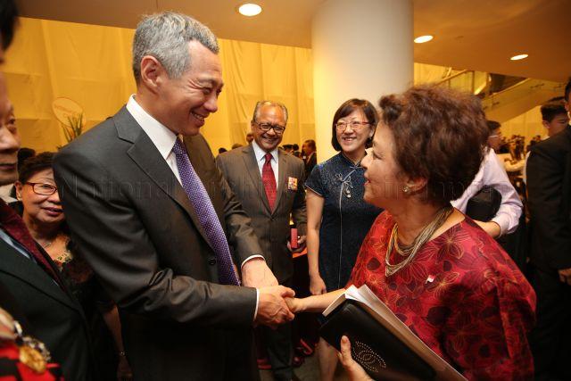 Prime Minister Lee Hsien Loong with Mrs Timothy de Souza, mother of Member of Parliament for Holland-Bukit Timah Group Representation Constituency (GRC) Christopher de Souza, at the reception during investiture of National Day awards at University Cultural Centre, National University of Singapore in Kent Ridge. Also present is her husband Timothy de Souza (centre, left), recipient of Public Service Star award.