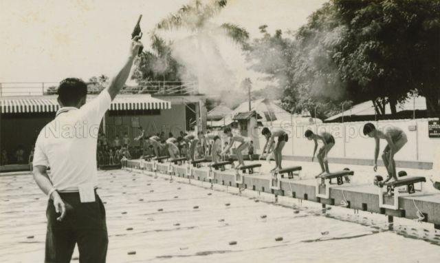 Starter pistol being fired to signal the start of a swimming competition