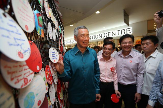 Prime Minister Lee Hsien Loong placing &nbsp;his wish card on the 'Wish House' developed in conjunction with Singapore 50 (SG50) celebrations during National Day Rally at Institute of Technical Education (ITE) headquarters and College Central in Ang Mo Kio. Looking on are Minister for Education Heng Swee Keat (centre), who is also Chairman of SG50 Steering Committee, and Minister for Culture, Community and Youth and Second Minister for Communications and Information Lawrence Wong.