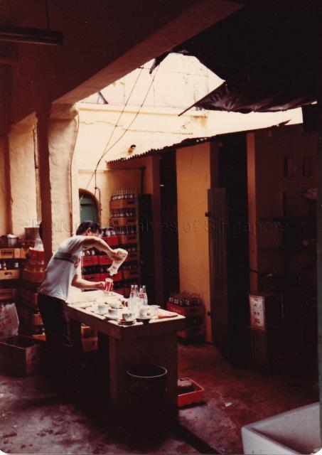 A coffee shop assistant clearing table at Sungei Road