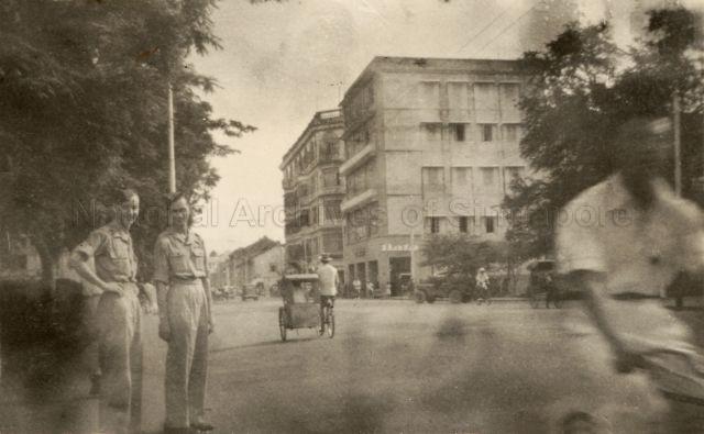 View of North Bridge Road taken outside of St Andrew's Cathedral, with Meyer Mansions (back) and Bata Building (front) in the background. Peninsula Plaza stands on the site of the two buildings today, with Bata still in operation.