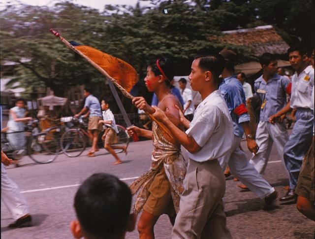 A young Chinese temple medium holding a sword and flag in a procession<br />