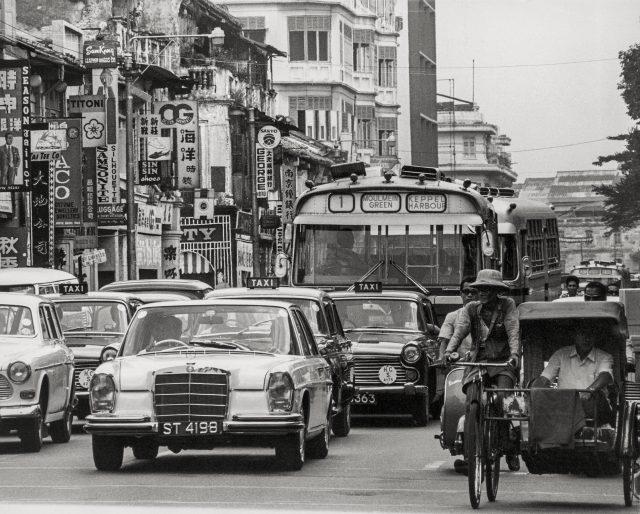 North Bridge Road was already a major road in the 1960s and all forms of transportation, from trishaws to Bus Number 1 of the Singapore Traction Company, shared the road. The Singapore Traction Company ran tramways in 1923 but ceased operation in 1971 in the face of competition from three other companies that eventually merged to become the Singapore Bus Services. Among the signage at the bustling shopping area, we can see Ocean Garments with one of its early retail outlets at 71 North Bridge Road. It is now better known simply as â€œOGâ€ and has a chain of large department stores.