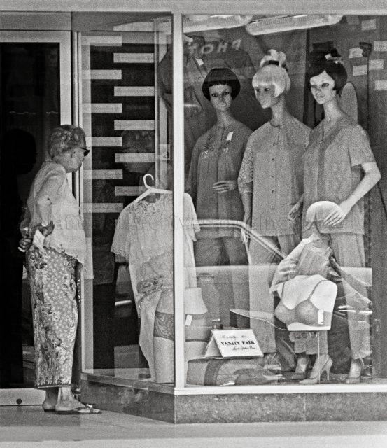 An elderly lady in a traditional sarong kebaya window-shopping for â€œwestern apparelâ€.