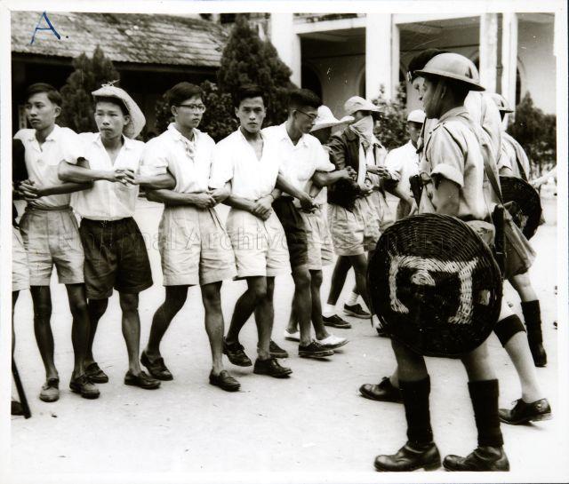 This photograph illustrates one of the incidents in the Report on Military Action taken in the Singapore Riots, 25 October to 2 November 1956. Police clearing students from the Chinese High School.