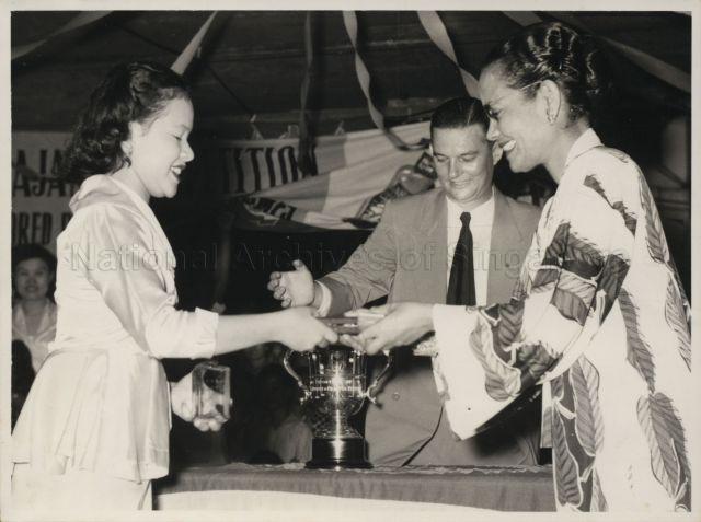The Honorable Datin Puteh Mariah presents "Miss Kajang" with her prize as District officer, Mike Gorrie looks on